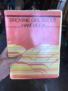 the brownie girl scout's hand book is held up in front of it