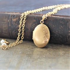 "A lovely gold filled locket graces this necklace. The vintage piece has a lovely floral design etched on the front; the back is plain. The gold filled pendant is hallmarked on the inside which has two frames to place your beloved photos. The locket has been set on a new 14k gold filled chain accented with tiny white pearls at the clasp. Locket 25x15mm Necklace 18\" (45cm) ✦All of our vintage lockets ship with complimentary insurance✦ ✤Our entire selection of lockets can be found here✤ http://ww Gold Locket Necklace With Vintage Charm, Gold Pendant Locket Necklace With Vintage Charm, Gold Heirloom Brass Locket Necklace, Heirloom Gold Brass Locket Necklace, Heirloom Brass Necklace For Keepsake, Vintage Gold Locket Jewelry, Classic Gold Locket Necklace With Vintage Charm, Antique Gold Necklace With Vintage Charm For Keepsake, Gold Brass Locket Jewelry