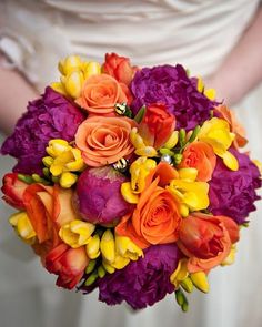 a bridal bouquet with orange and purple flowers on the bride's wedding day