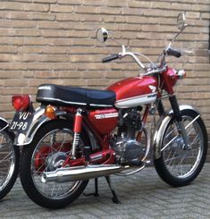 a red motorcycle parked next to a brick wall