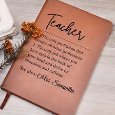 a brown leather book with the words teachers written on it next to some dried flowers