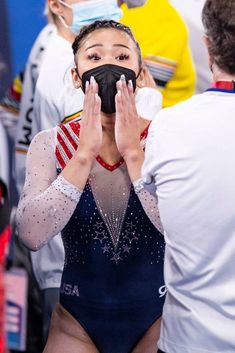 a woman is covering her face while standing in front of some other people wearing masks