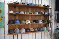 many hats are lined up on wooden shelves