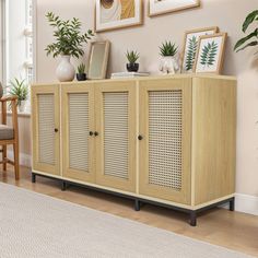 a wooden cabinet sitting in the middle of a living room next to a chair and potted plant