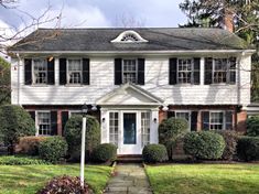 a large white house with black shutters on the front and side windows is shown