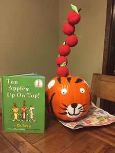 an orange pumpkin sitting on top of a wooden table next to a book and toy