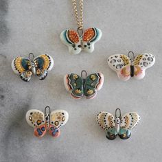 six butterfly shaped pendants on a silver chain, all with different colors and designs