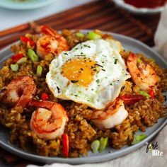 rice with shrimp and fried egg on top is served on a plate, ready to be eaten