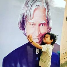 a young boy hugging an older man's face in front of a large poster