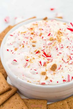 a white bowl filled with candy canes and whipped cream surrounded by crackers on the side