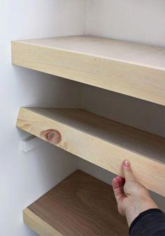 a person is reaching for some shelves on the wall with their hand in front of them