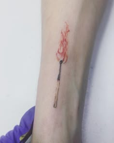 a person with a tattoo on their arm has a fire stick in the shape of a heart