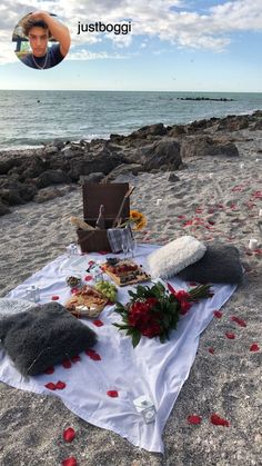 a picnic set up on the beach with food and flowers