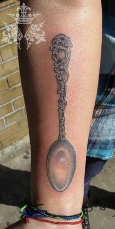 a person with a tattoo on their arm has a spoon in the shape of a key