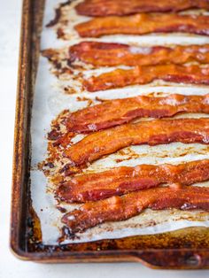 bacon strips are lined up on a baking sheet