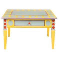 a yellow table with red and blue dots painted on the top, sitting in front of a white background