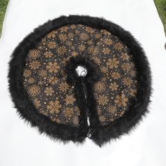 a black and gold hat sitting on top of a white cloth covered table next to grass