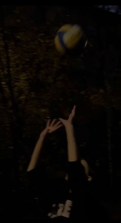 two people reaching for a volleyball in the dark