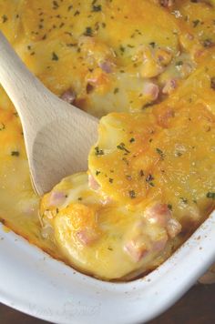 a wooden spoon in a casserole dish with ham and cheese