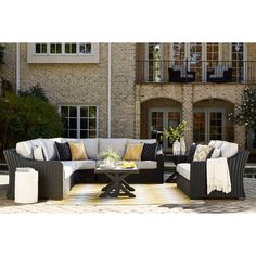 an outdoor patio furniture set in front of a brick building with white and yellow pillows