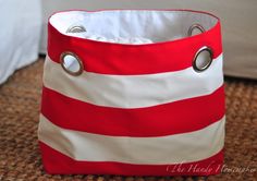 a red and white striped bag sitting on top of a carpet next to a bed