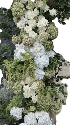 an arrangement of white flowers and greenery on a bench