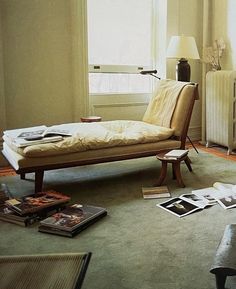 a living room filled with furniture and books on the floor next to a radiator