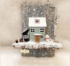 there is a small house with snow on the roof and two teddy bears in front