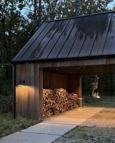 a garage with wood stacked in it and lights shining on the side of the building