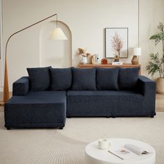 a living room with a blue couch and coffee table in the corner, next to a lamp