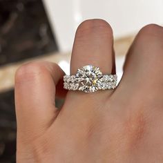 a woman's hand with a diamond ring on top of her finger and an engagement band