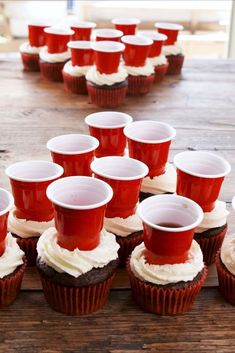 cupcakes with white frosting and red cups sitting on top of each other