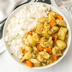 a white bowl filled with rice and vegetables next to a fork, spoon and napkin