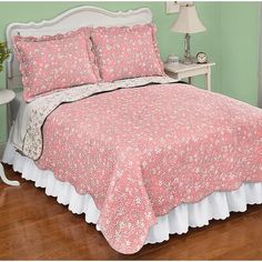 a bed with pink and white bedspread in a bedroom next to a lamp