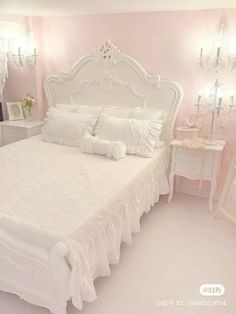 a white bed in a pink bedroom with chandelier and mirror on the wall