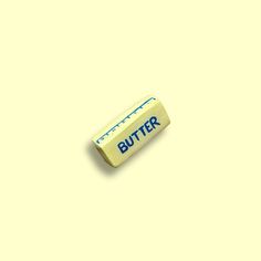 a butter stick sitting on top of a yellow surface with the word butter written on it