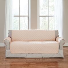 a living room with two windows and a couch covered in a quilted pink cover