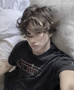 a young man laying on top of a bed next to a teddy bear