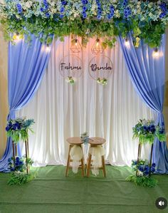 a blue and white wedding setup with flowers on the back drop cloth draping