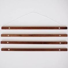 three pieces of wood hanging on a wall with white paint and wooden pegs attached to it