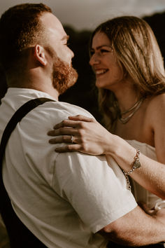 a man and woman standing next to each other with their arms wrapped around each other