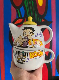 a hand holding a ceramic teapot with an image of betty boop on it