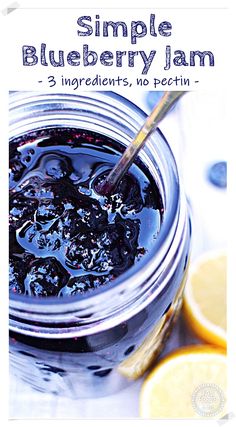 a jar filled with blueberry jam sitting on top of a table next to sliced lemons