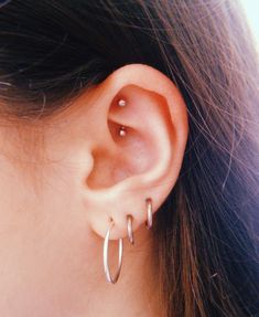 a close up of a person's ear with two small hoops on it