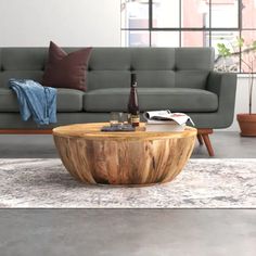 a wooden table sitting on top of a carpeted floor next to a gray couch