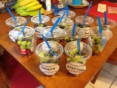 several cups filled with different kinds of fruit on top of a wooden table next to bananas and other items