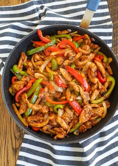 a skillet filled with chicken, peppers and onions