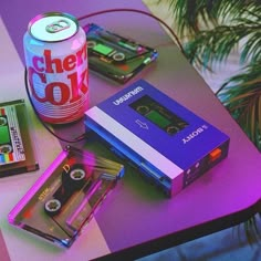 a table topped with different types of games and cassettes next to a can of soda