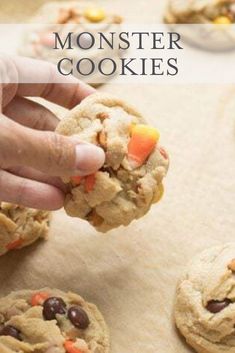 a person holding a cookie with chocolate chips and candy corn on it, in front of other cookies