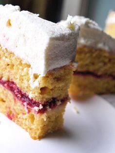 two pieces of cake with white frosting and raspberry toppings on a plate